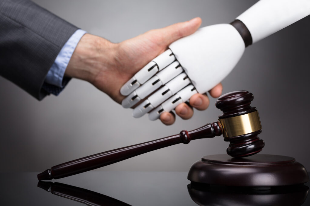 Human shaking hands with robot over judicial gavel